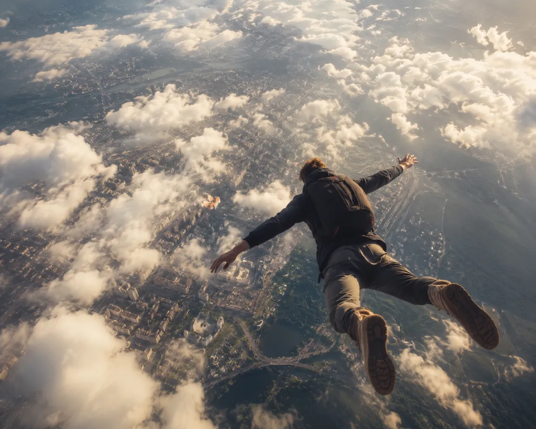 A person seen from above, soaring high with the city far below their feet