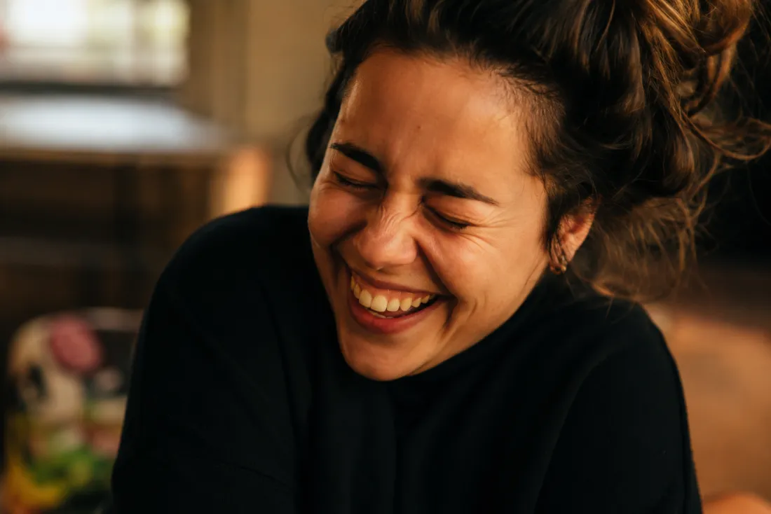 Close-up of a laughing person showing crinkled eyes, lifted cheeks and shaking shoulders