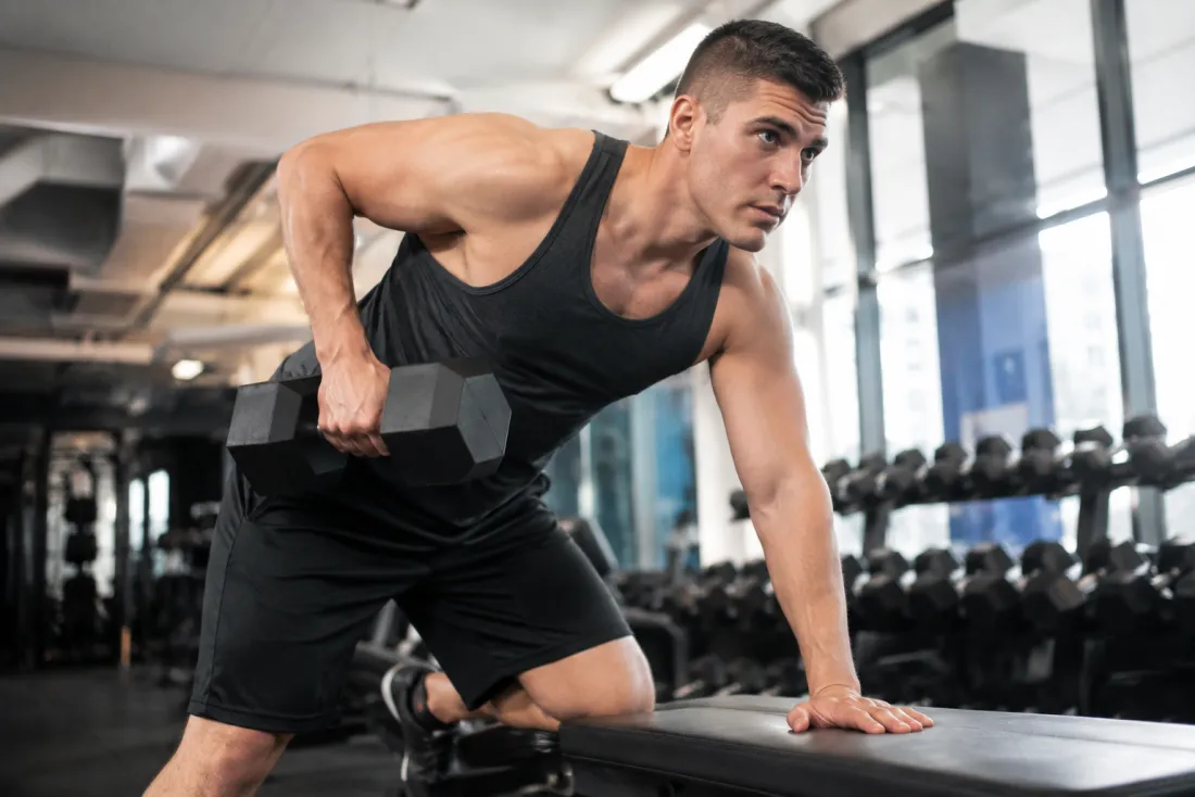 Fit figure in mid-rep workout motion inside a gym setting