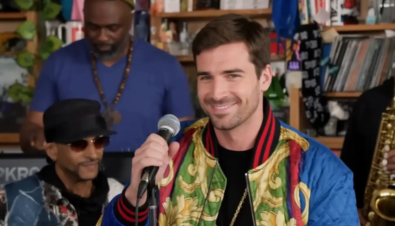 Final frame of the same actual video, the new lead smiling at the microphone