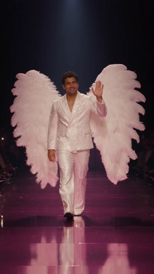 Opening frame from the actual runway sample, adult performer waving in white feather wings