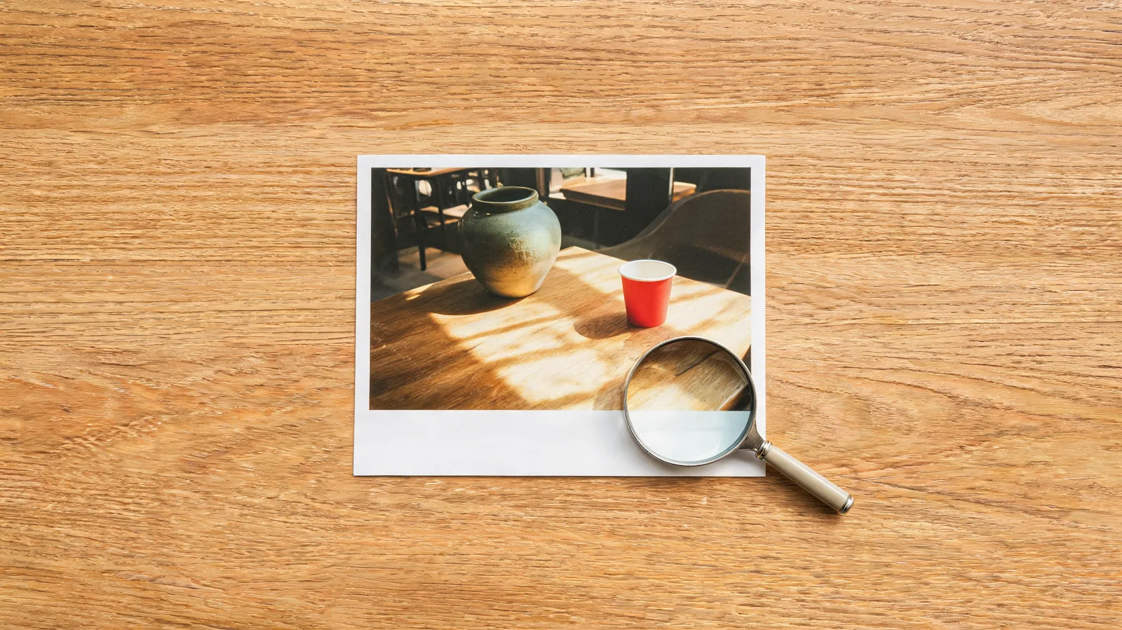 Conceptual editorial illustration of a cafe photo print and a magnifying glass for close inspection